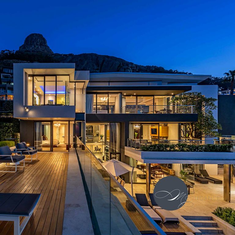 Moondance Villa
50 Moondance is filled with an endless list of distinctive features which coupled with Antoni’s careful consideration to facilities and functionality provides the perfect residence for an unrivalled, multi-sensory vacation. Bold, dramatic architectural features like the unique staircase above an indoor water feature are met with incredible finishes and furniture throughout the home. The koi pond, indoor cinema, spit braai, pizza oven and multiple private, outdoor entertainment areas are world class bonuses to this property.
With the smell of a famous South African barbeque wafting through the air, music playing, sport on in the background, cocktails in hand; either tanning on the sun loungers or getting respite from the heat in the pool, 50 Moondance is the perfect space to soak up every bit of the best summer has to offer, in one of the most wind-protected locations on the Peninsula.
With 4 en-suite bedrooms all luxuriously finished to the highest of standards, this house will ensure complete comfort and relaxation during your stay. The 260m2 main bedroom, with en suite bathroom and walk-in closets boats some of the finest vistas Frensaye has to offer. The rooms are laid out in such a way to ensure maximum privacy for all guests.
4 x bedrooms (all en-suite) & 6 bathrooms
2 Garages (a triple and double garage fits 5 cars) – 5 outside parking bays
Manned Security Entrance
260m2 Master Bedroom, en suite & walk-in closets
Elevator through 4 levels
Extensive indoor & outdoor Koi pond
Outdoor braai/pizza oven entertainment area (1)
Outdoor tanning deck braai area (2)
Outdoor lounge & leisure area (3)
Lower level outdoor seating & leisure area (4)
Magnificent Olive Grove with cobbled area for long lunches
16-seater Ostrich Leather dining room
3 x HD TV Lounges
HD Cinema with surround sound
3 x Bars with fridges & ice machines
Under-pool fully-equipped bar – glass panels show underwa